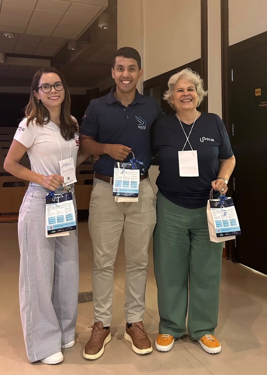 Michele Amaral Brandão, Ramon Gonçalves Pereira e Mariangela Leal Cherchiglia, lado a lado, segurando as sacolas do CI-IA Saúde
